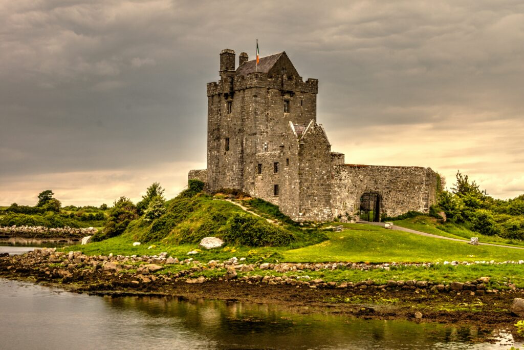 A castle in Ireland, surrounded by emerald green grass and crystal clear water.